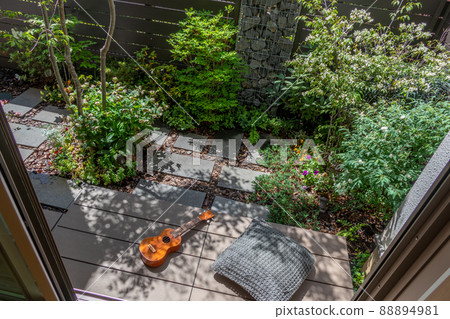 Enjoy the ukulele in the sun on the porch in a small garden with a gabion 88894981