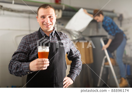 Portrait of positive man brewmaster with glass of beer Portrait of positive man brewmaster with glass of beer 88896174