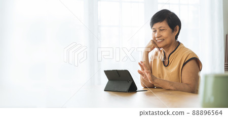 Asian Mature woman using digital tablet computer at home 88896564