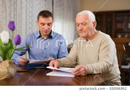 Mature man and realtor fills in documents for purchase of apartment Mature man and realtor fills in documents for purchase of apartment 88896862
