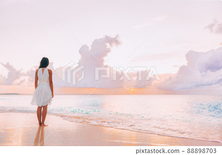 Paradise beach elegant woman walking relaxing watching pink sunset on idyllic travel Caribbean vacation destination. Clouds and ocean serene scenery relaxation Paradise beach elegant woman walking relaxing watching pink sunset on idyllic travel Caribbean vacation destination. Clouds and ocean serene scenery relaxation 88898703