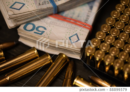 Close-up view of rifle and pistol ammunition and fifty dollar bills. 88899379