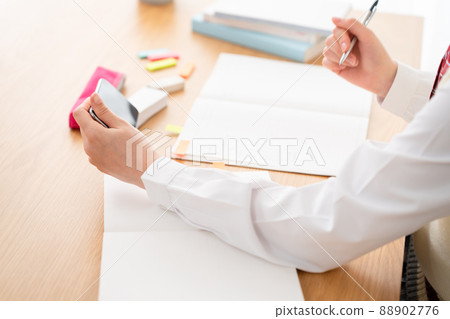 High school girl studying while watching a smartphone High school girl studying while watching a smartphone 88902776