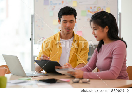 Male and female marketing workers working and planning the project together Male and female marketing workers working and planning the project together 88902940