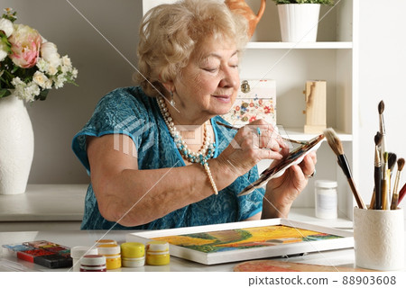 A retired woman paints a picture in the studio 88903608