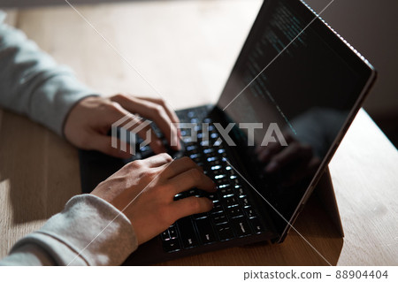 Male hacker writing code on a laptop Male hacker writing code on a laptop 88904404