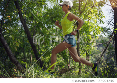 Woman runner running on forest trail Woman runner running on forest trail 88905250