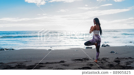 woman in sport clothes practicing yoga and meditating on beach in morning woman in sport clothes practicing yoga and meditating on beach in morning 88905825