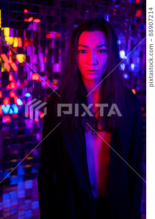 Close-up portrait of an androgenic model. Male transgender in studio with neon light. Close-up portrait of an androgenic model. Male transgender in studio with neon light. 88907214
