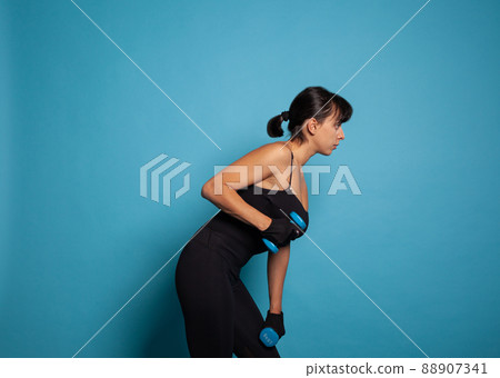 Active athletic trainer woman in sportwear training arm muscles practicing fitness exercices using dumbbells working at healthy lifestyle in studio. Concept of sport woman Active athletic trainer woman in sportwear training arm muscles practicing fitness exercices using dumbbells working at healthy lifestyle in studio. Concept of sport woman 88907341