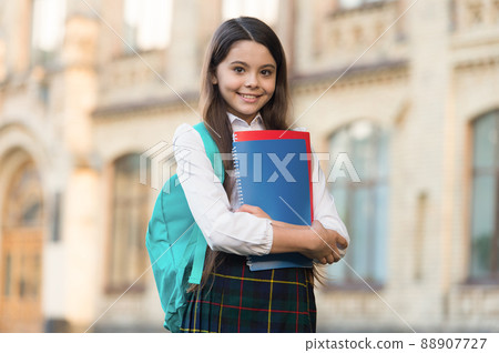 Little girl student school uniform and backpack hold books, formal education concept Little girl student school uniform and backpack hold books, formal education concept 88907727