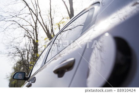 Expensive fuel for the car. Alternative energy. A woman opens a tank for refueling gasoline. Harmful gas emissions into the air Expensive fuel for the car. Alternative energy. A woman opens a tank for refueling gasoline. Harmful gas emissions into the air 88910424