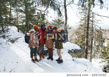 High angle view wide shot of young multi-ethnic friends hiking together in mountains choosing route using map app on smartphone High angle view wide shot of young multi-ethnic friends hiking together in mountains choosing route using map app on smartphone 88910560