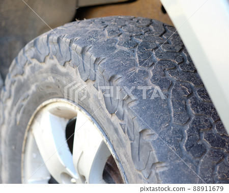 A bald tire on a car that needs to be replaced with a new one 88911679