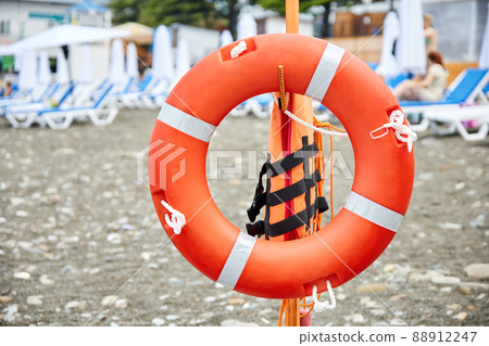 Lifebuoy on a pebble beach against the background of sun loungers Lifebuoy on a pebble beach against the background of sun loungers 88912247