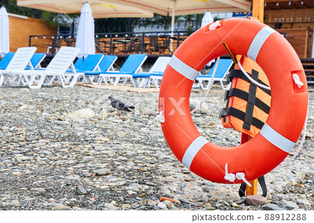 Lifebuoy on a pebble beach against the background of sun loungers Lifebuoy on a pebble beach against the background of sun loungers 88912288