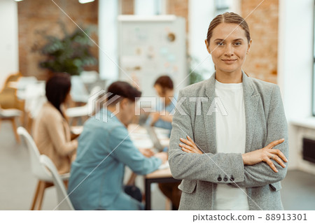 Smiling woman standing in a coworking space and clasped her hands 88913301