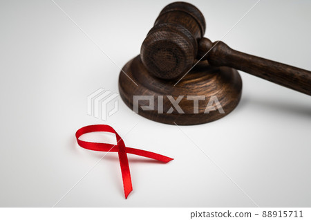 Judicial gavel and red ribbon on a white background. Symbol of the fight against AIDS. 88915711