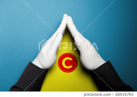 Hands in white gloves showing a yellow triangle with a copyright sign. The concept of creativity and ideas. International Intellectual Property Day Hands in white gloves showing a yellow triangle with a copyright sign. The concept of creativity and ideas. International Intellectual Property Day 88916765