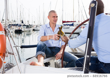 A couple of guys in blue shirts and jeans chatting on a private yacht in port A couple of guys in blue shirts and jeans chatting on a private yacht in port 88916766
