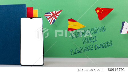 Cellphone apps for learning foreign languages. A smartphone, book and paper airplanes with Spanish, English and Chinese flags. Mock up. The concept of learning foreign languages 88916791