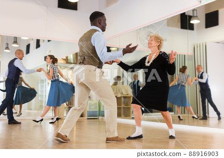 Lady learning to dance lindy hop with man in dance school Lady learning to dance lindy hop with man in dance school 88916903