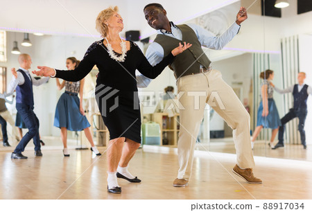 Woman pensioner with african man practising charleston 88917034