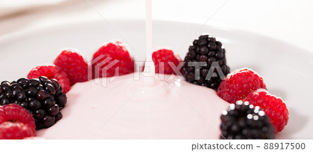 fresh raspberries and blackberries laid out on a white plate in circle with yogurt 88917500