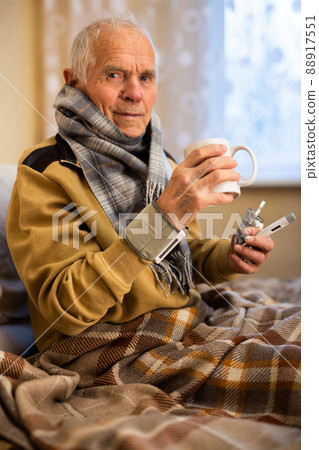 gray haired elderly man is sick and drinking hot tea at home gray haired elderly man is sick and drinking hot tea at home 88917551