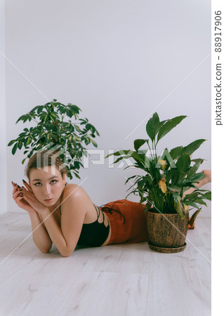 Portrait of young caucasian woman in red cloth laying near flowerpot 88917906