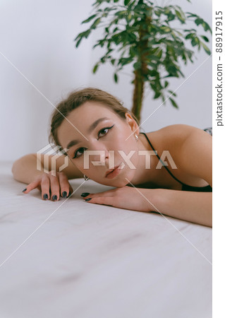 Portrait of young caucasian woman in red cloth laying near flowerpot 88917915