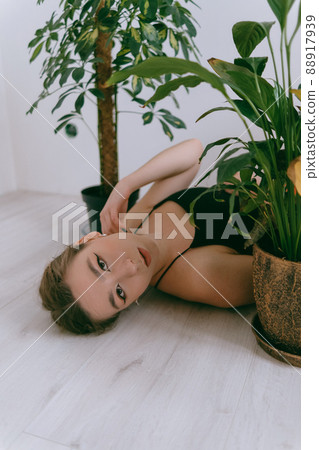 Portrait of young caucasian woman in red cloth laying near flowerpot Portrait of young caucasian woman in red cloth laying near flowerpot 88917939