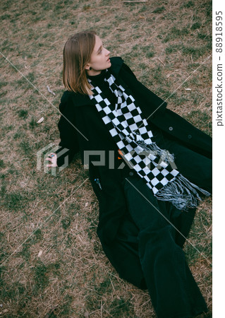woman in black coat sitting on the ground in the park 88918595