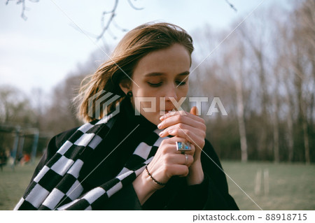 portrait of a girl sitting in the park and happily smoking marijuana 88918715