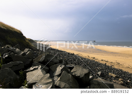 Black rocks and beach sand on stormy day at Hartlepool Headland, UK 88919152