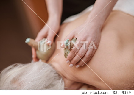 Professional doing hot bags massage to a client 88919339