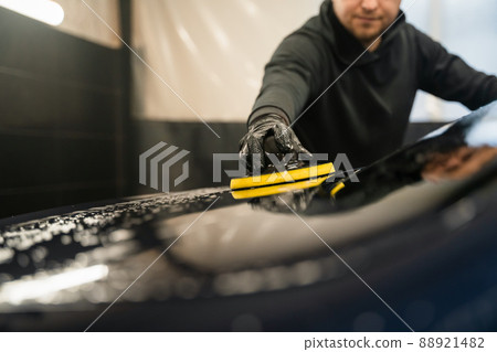 Man cleans rear window of car with  circle sponge. Professional car wash process 88921482