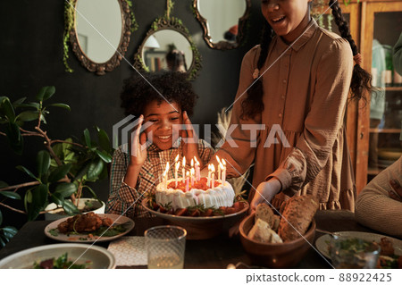 African little boy looking at birthday cake with excitement at table while celebrating birthday with family 88922425