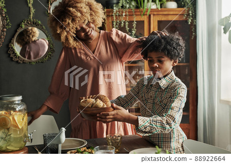African little boy serving plate with bread on table for dinner, he helping to his mother African little boy serving plate with bread on table for dinner, he helping to his mother 88922664
