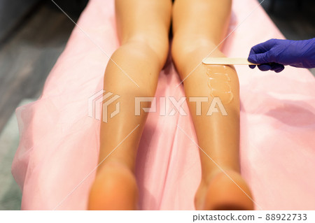 Beautician applies laser depilation gel to the patient's legs 88922733