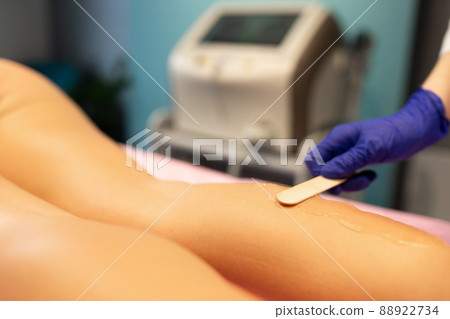 Beautician applies laser depilation gel to the patient's legs 88922734