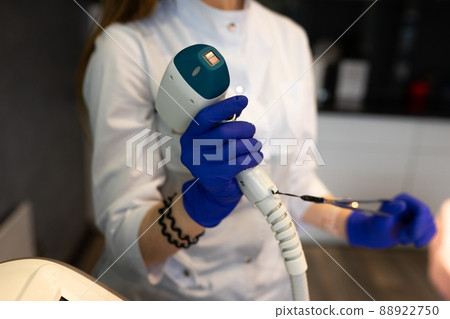 Female cosmetologist with a laser for hair removal 88922750
