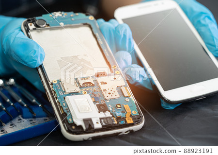 Technician repairing inside of mobile phone by soldering iron. Integrated Circuit. the concept of data, hardware, technology. Technician repairing inside of mobile phone by soldering iron. Integrated Circuit. the concept of data, hardware, technology. 88923191
