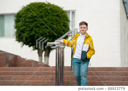 Schoolboy with backpack going down the stairs from school. Teenager comes home after class Schoolboy with backpack going down the stairs from school. Teenager comes home after class 88923779