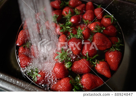 Juicy ripe red strawberries are washed in a steel bowl full of water. 88924847