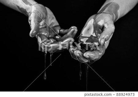 Women's hands in a viscous liquid similar to blood. Black and white photo. 88924973