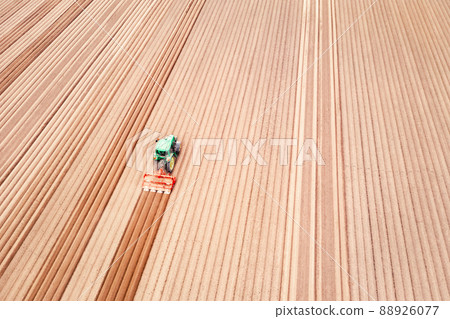 Lonely tractor on agricultural field with rows of plowed soil 88926077