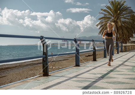 Sporty young woman jogging on sidewalk in public park 88926728