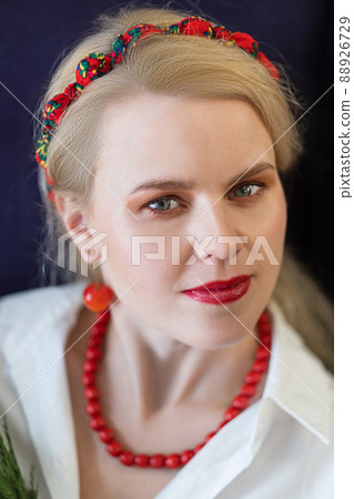Close-up portrait of a blonde young woman with creative makeup and red accessories 88926729