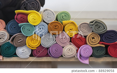 Multi-colored knitted fabrics rolled up in rolls lying on shelf of store, factory Multi-colored knitted fabrics rolled up in rolls lying on shelf of store, factory 88929058